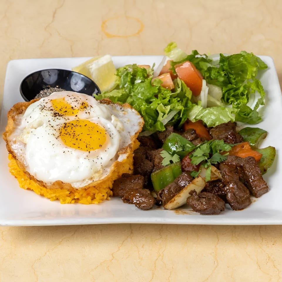 Savory beef stir-fry with bell peppers, onions, cilantro, fried eggs, yellow rice, and a side salad.